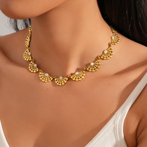 Détail du collier doré en forme d'éventail avec cristaux porté par un mannequin