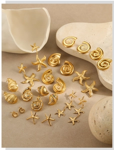 Detailed collection of 18K gold plated seashell and starfish earrings on a sandy background
