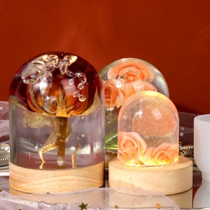 Close-up of preserved rose resin domes on wooden base with warm light effect