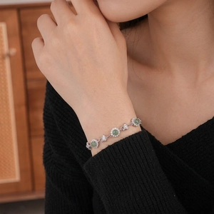 Bracelet fleurs élégant avec pierres vertes et zircons porté sur un poignet féminin