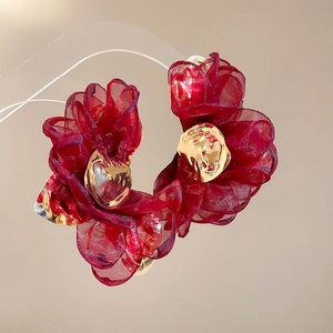 Close-up of elegant red organza flower earrings with gold center on display stand