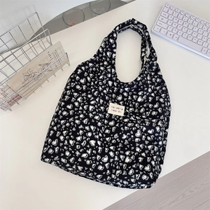 Detail of canvas tote bag showing black and white heart pattern and woven label