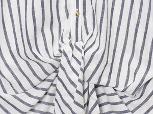 Dettaglio macro della camicia in lino a righe con nodo frontale e bottone dorato fine