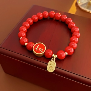 Détail d'un bracelet en perles rouges avec un pendentif doré Fu sur un coffret