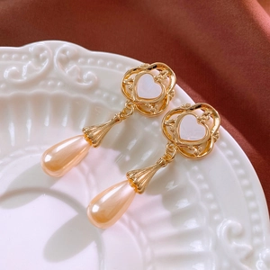 Détail des boucles d'oreilles cœur vintage dorées avec perles gouttes rose champagne
