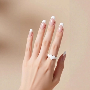 Minimalist white heart ring on finger with elegant French manicure nails