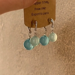 Close-up of minimalist water drop resin earrings with blue cat-eye stone beads detail