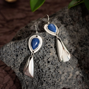 Detail of bohemian silver leaf earrings with lapis blue stones on volcanic rock