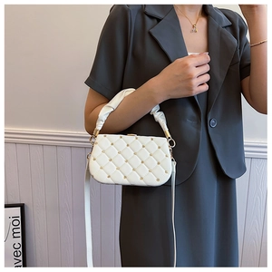 Close-up of white quilted box bag with floral rivets and pleated cloud handle on model