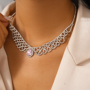 Close-up of a silver-toned luxury necklace featuring a sparkling pink pear-cut gemstone