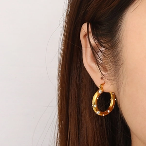 U-shaped gold titanium steel earrings with cubic zirconia on a model's ear