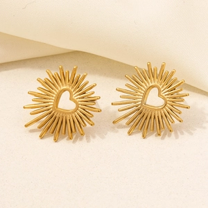 Detailed view of gold heart-shaped stud earrings with radiant sunburst metal texture