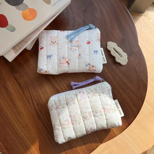 Close-up of quilted cotton pouches with cute animal patterns and woven zipper pulls