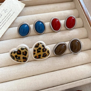 Close-up of four pairs of vintage acrylic earrings including leopard heart and oval studs