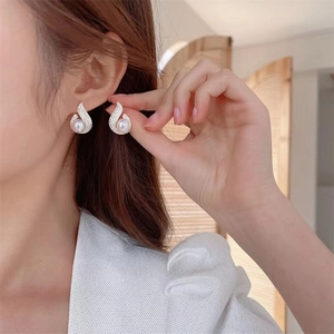 Close-up of elegant teardrop pearl earrings with pavé zircons on a model's ear