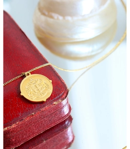 Gros plan d'un pendentif amulette en or 18k avec gravure Victoria dans une boîte cadeau rouge