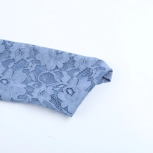 Detail of delicate blue lace cuff featuring intricate floral patterns and fine mesh texture