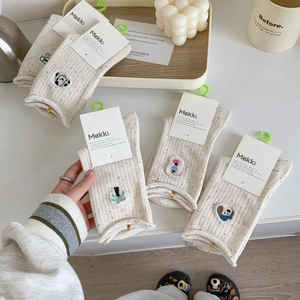 Gros plan de chaussettes en coton beige tricoté avec broderie et bord roulé pour femmes