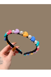Detail of colorful heart beads and white pearls on a black fabric headband band