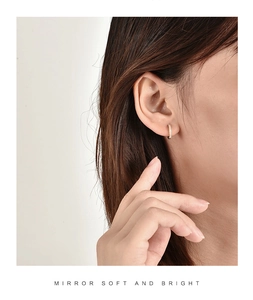 Close-up of minimalist gold hoop earrings with small zircon stones worn by a model