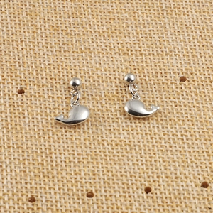 Vue détaillée de boucles d'oreilles baleine en acier inoxydable argenté sur un tapis tissé
