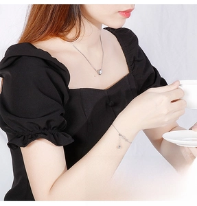 Close-up of heart pendant necklace and matching silver bracelet on model for a chic look