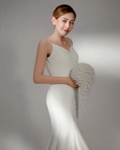 Detailed view of elegant white satin bridal gown with luxury handmade pearl bouquet