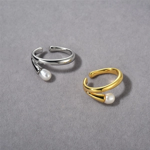 Detailed close-up of adjustable gold and silver rings with elegant white pearl accents