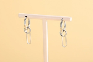 Silver multi-layered circular stainless steel earrings displayed on a white T-stand
