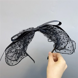 Detail of a large black polka dot mesh bow headband with elegant satin ribbon textures