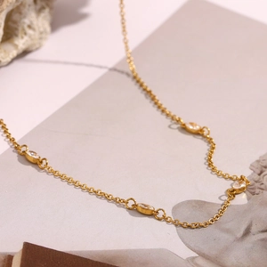 Detail of 18K gold plated necklace with marquise-cut zircons on a textured stone