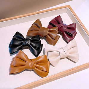 Détail de barrettes à nœuds en cuir PU de couleurs noir, marron, bordeaux et crème