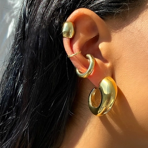 Macro shot of tiered 18k gold stainless steel ear cuffs and classic C-shaped earrings