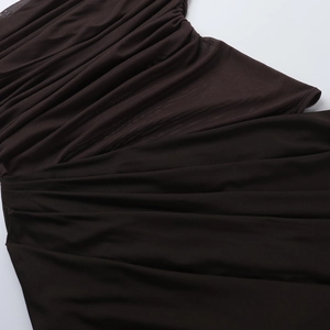 Close-up of ruched mesh and knit fabric stitching on a dark brown backless halter dress