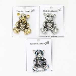 Three rhinestone teddy bear brooches in gold, silver, and antique colors on card display