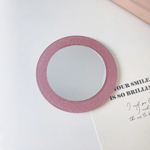 Detail eines tragbaren runden Schminkspiegels mit rosa Glitzer und antistatischem Kamm