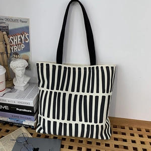Detailed view of the black and white striped canvas tote bag on a stylish wooden stool