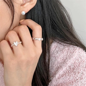 Close-up of 925 sterling silver heart rings and pearl earrings worn by a model