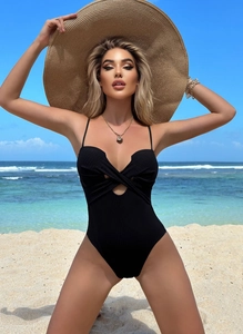 Detail of ribbed black one-piece swimsuit with cutout twist front on a beach