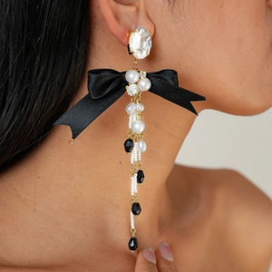 Detail of long bow tassel earrings with crystals, pearls and black ribbon on model
