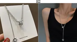 Detail of silver asymmetric chain necklace with cross cylinder and pearl star charm
