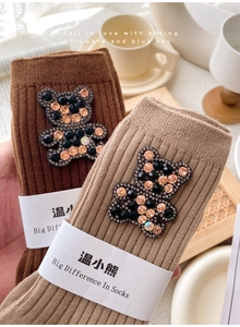 Close-up of cotton mid-tube socks with sparkling rhinestone bear patches and paper band