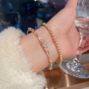 Close-up of 18K gold plated bangle set featuring square zircon stones in a lifestyle shot