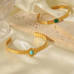 Detail of vintage gold-plated stainless steel bangles with green and blue stones on silk