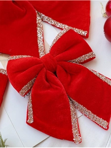Close-up of red velvet Christmas bow with gold glitter edges for tree decoration