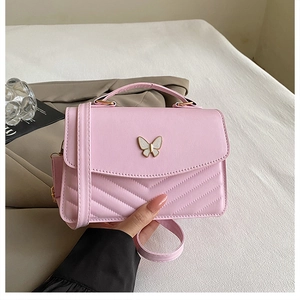 Detail of pink leather handbag featuring a butterfly metal clasp and V-shape stitching