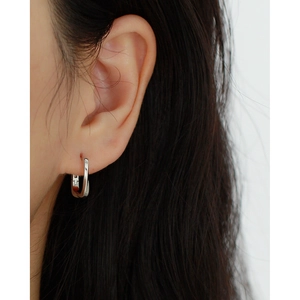 Close-up of minimalist S925 silver twisted geometric hoop earring worn on model's ear