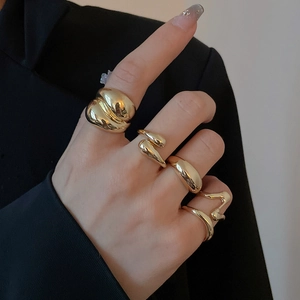 Close-up of a model wearing four different polished gold irregular streamline rings