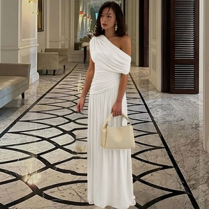 Detail of elegant white off-shoulder ruched maxi dress with flowing silhouette in indoor setting