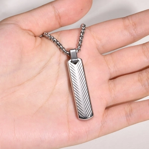 Macro shot of silver rectangular pendant with intricate feather texture engraving and chain